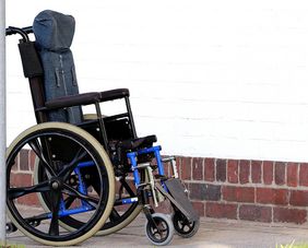 Ein leerer Rollstuhl steht vor einer weißen Wand