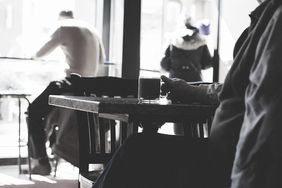 Mann sitzt am Tisch mit Kaffeetasse