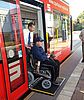Rollstuhlfahrer wird von Person aus Straßenbahn geschoben