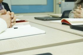 Hände am Tisch mit aufgeschlagenen Heften - Blick auf Verhandlungssituation