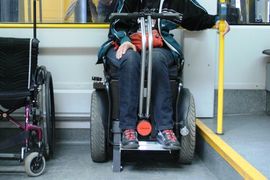 Bildausschnitt Beine eines Rollstuhlnutzers in der Straßenbahn