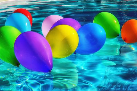 verschiedenfarbige Ballons die in einem Schwimmbecken auf dem Wasser treiben