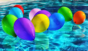 [Translate to Leichte Sprache:] verschiedenfarbige Ballons die in einem Schwimmbecken auf dem Wasser treiben