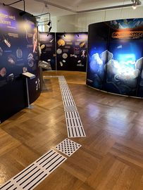 Blindenleitsystem im Senckenbergmuseum umgeben von Aufstelltafel einer Ausstellung
