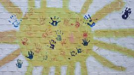 gemalte Sonne mit bunten Handabdrücken in der Mitte