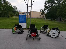 verschiedene Rollstühle vor Rollup gestellt