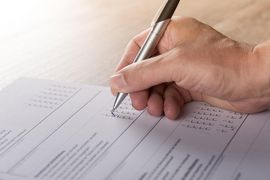 Hand mit Kugelschreiber und dem Ausfüllen eines Formulars