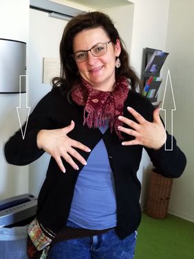 Frau mit Brille und langen Haaren zeigt die Gebärde spielen