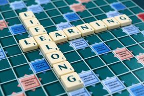 Ein Scrabble-Brett auf dem die Worte "Livelong" und "Learning" im Buchstaben "E" gekreuzt miteinander verbunden sind.