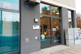 [Translate to Leichte Sprache:] Der Eingangsbereich des ADB Büros in Dresden. Eine breite Glastür mit diversen Hinweisen und einem gelben Pfeil, der auf diese Hinweise zeigt.