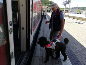 Fahrgast mit Blindenführhund steigen in den Zug