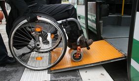 Rollstuhlnutzer fährt Rampe hoch in den Zug