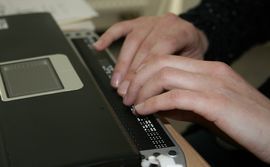 Braille-Leiste am Laptop angeschlossen - Blick auf schreibende Hände